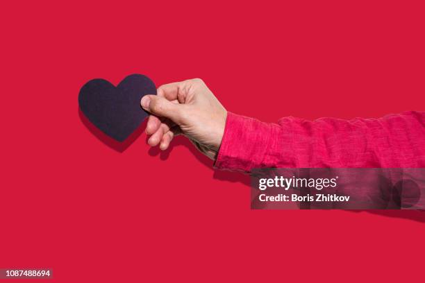 male hand holding black paper heart - hand sleeve stock pictures, royalty-free photos & images