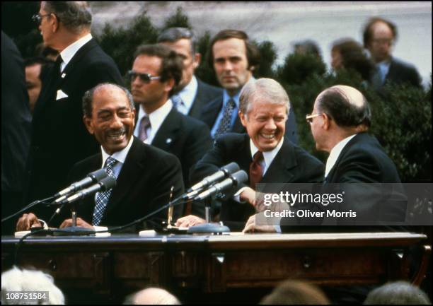 Egyptian President Anwar El Sadat smiles as he watches American President Jimmy Carter shakes the hand of Israeli Prime Minister Menachem Begin after...