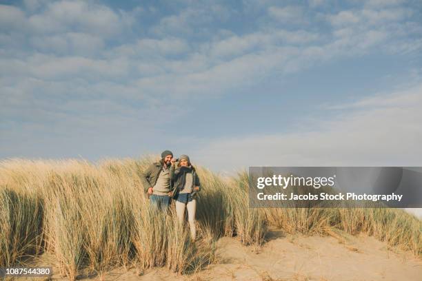 couple standing on a beach - couple dunes stock-fotos und bilder