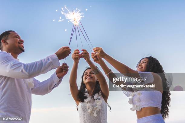 happy friends celebrating reveillon on the beach, holding sparklers. paraiso beach, mosqueiro - happy new year 2018 stock pictures, royalty-free photos & images