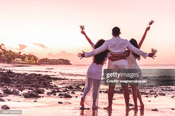 amigos felizes comemorando o reveillon na praia, abraçando um ao outro e segurando flores brancas. praia do paraiso, mosqueiro - reveillon - fotografias e filmes do acervo