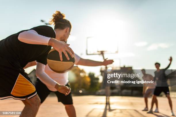 jeune homme jouant un bon moyen de défense - match basket photos et images de collection