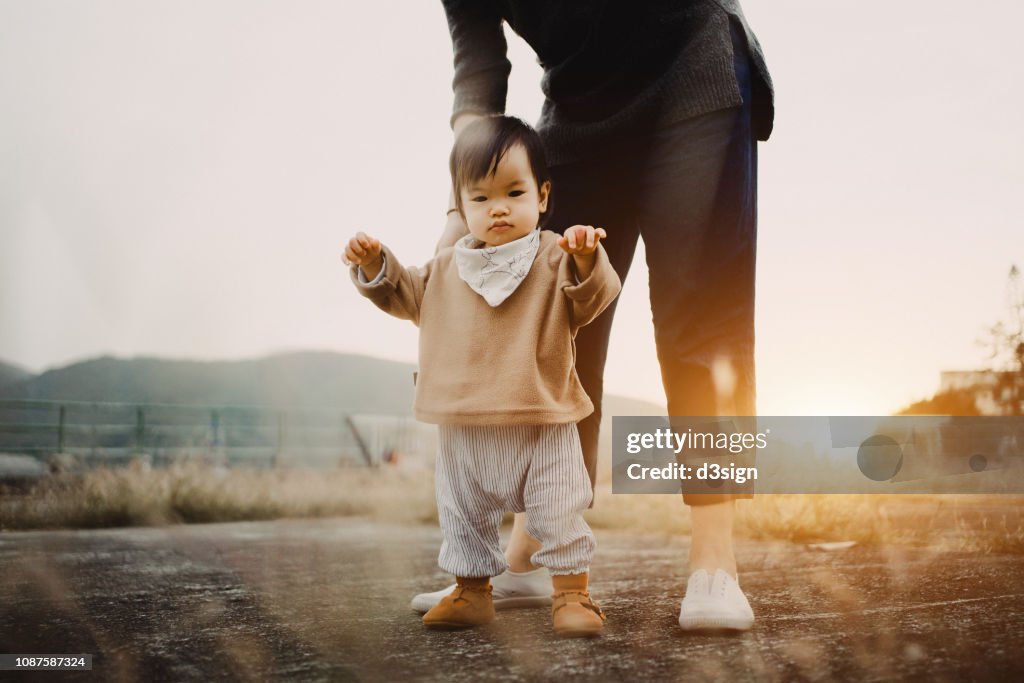 Baby Girl Holding Mothers Hand Walking In The Park With The Warmth