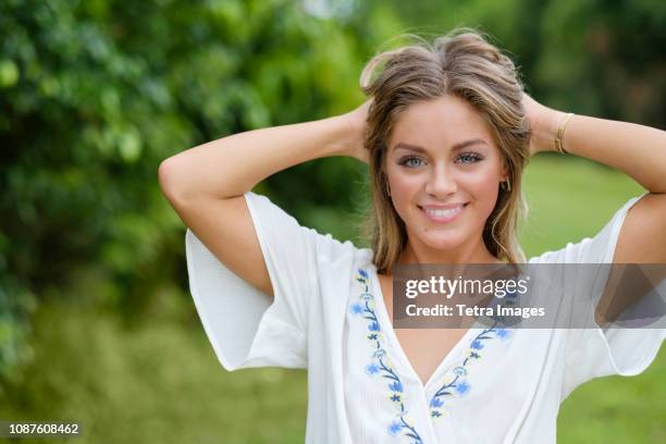 smiling young woman with hands in her hair - summer blouse stock pictures, royalty-free photos & images