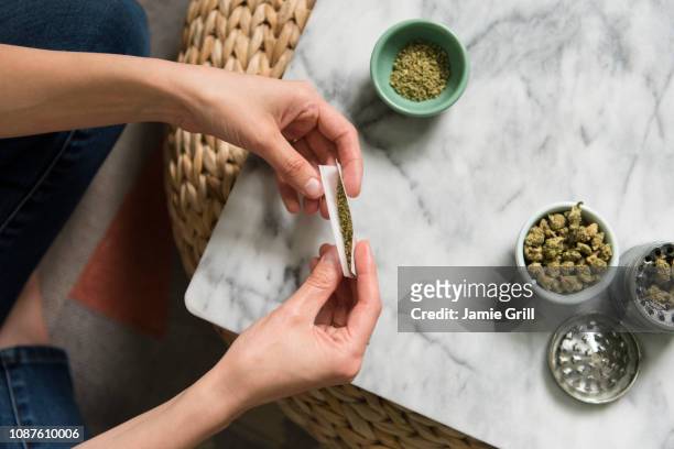 hands of woman rolling marijuana joint - spinello foto e immagini stock
