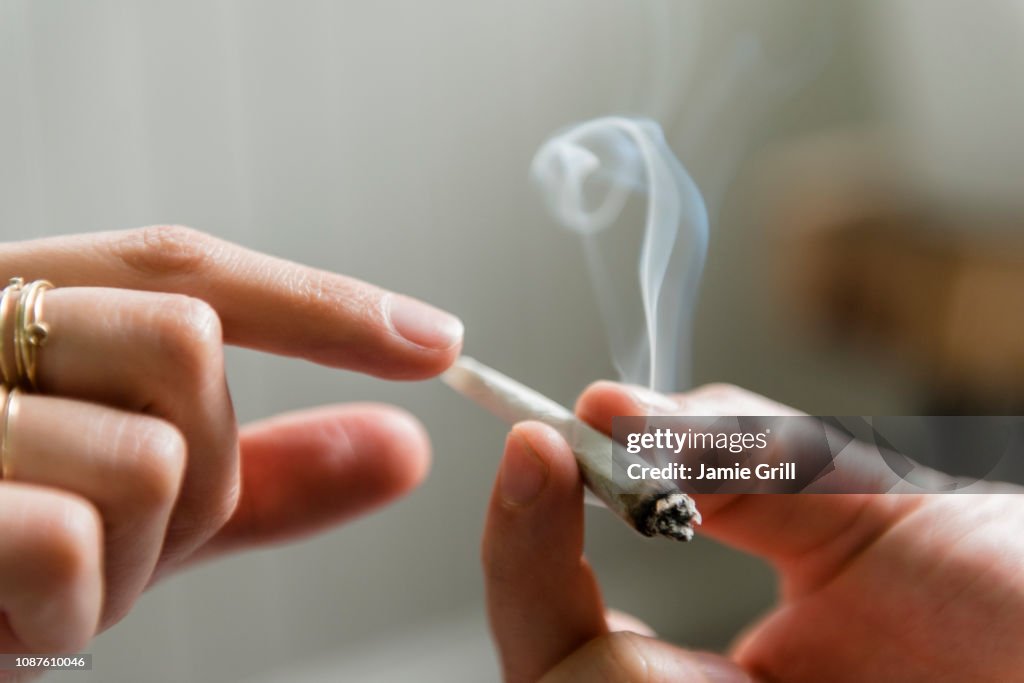 Hands of man and woman passing marijuana joint