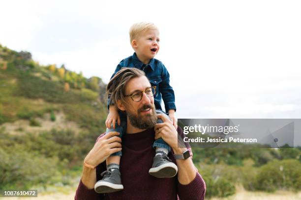 father giving son piggyback ride - llevar al hombro fotografías e imágenes de stock