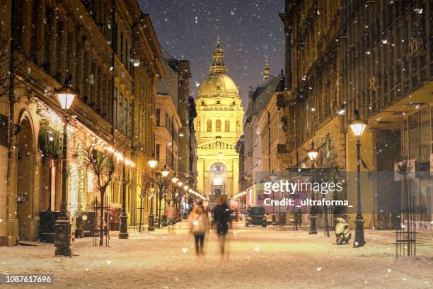 paesaggio urbano illuminato di via zrinyi a budapest con la basilica di santo stefano in un paesaggio invernale innevato al crepuscolo - budapest foto e immagini stock