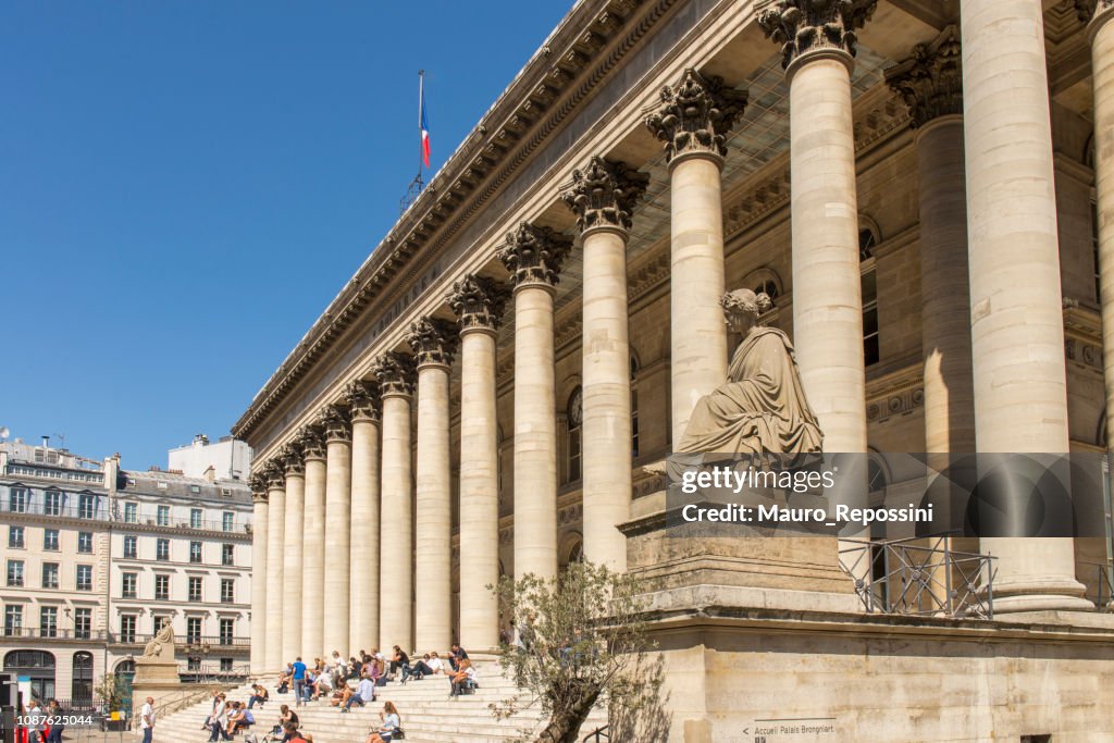 Mensen zitten op de trappen voor de Bourse du Paris-gebouw, bekend als Palais Brongniart, in de stad Parijs, Frankrijk.