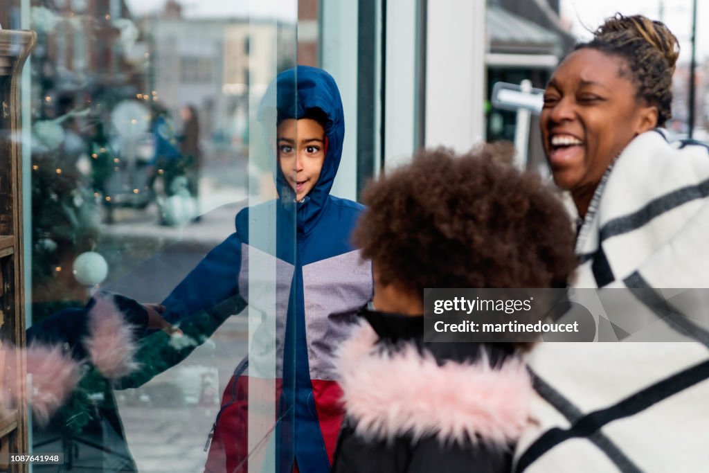Mixed-race family shopping on city street in winter.