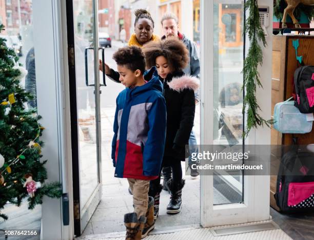 mixed-race family shopping on city street in winter. - entering shop stock pictures, royalty-free photos & images