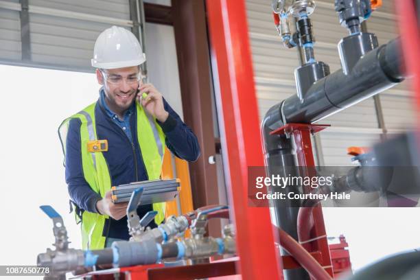pipeline engineer making call while inspecting oil and gas equipment - controle de qualidade imagens e fotografias de stock