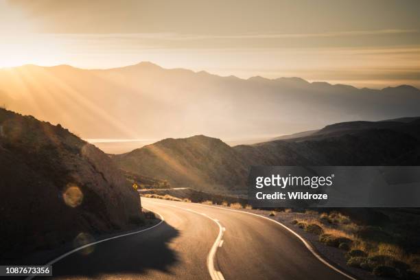 autobahn bei sonnenaufgang, in death valley nationalpark - straßenverkehr stock-fotos und bilder