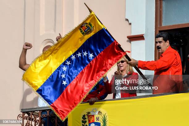 Venezuela's President Nicolas Maduro , flanked by his wife Cilia Flores , holds a Venezuelan flag while speaking from a balcony at Miraflores...