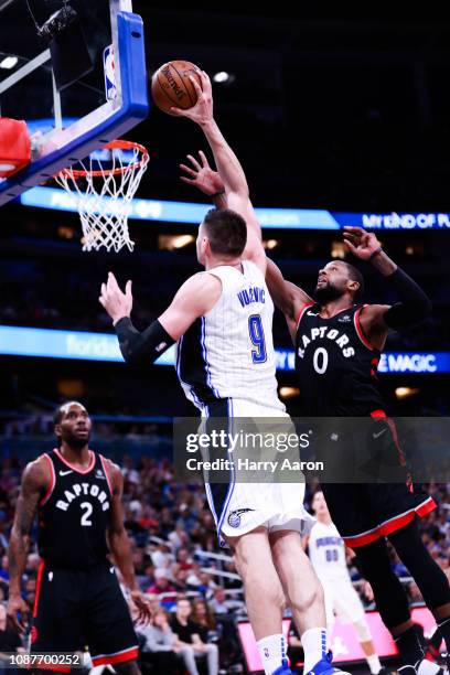 Nkola Vucevic of the Orlando Magic puts up a basket against C.J. Miles of the Toronto Raptors in the third quarter at Amway Center on December 28,...