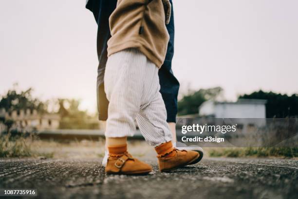 close up low section of baby girl learning to walk with mother in park - första stegen bildbanksfoton och bilder