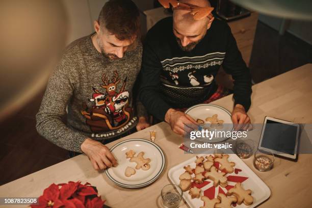 gay couple at christmas time - man baking cookies stock pictures, royalty-free photos & images