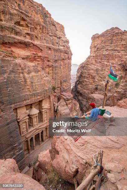 man, tourist looks from above into the gorge siq, pharaoh's treasure house beaten into rock, facade of the treasure house al-khazneh, khazne faraun, mausoleum in the nabataean city petra, near wadi musa, jordan - the cemetery for foreigners stock pictures, royalty-free photos & images