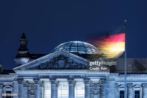 reichstag building with inscription on the west portal "dem deutschen volke" with german flag (berlin, germany) - reichstag berlin nacht stock-fotos und bilder