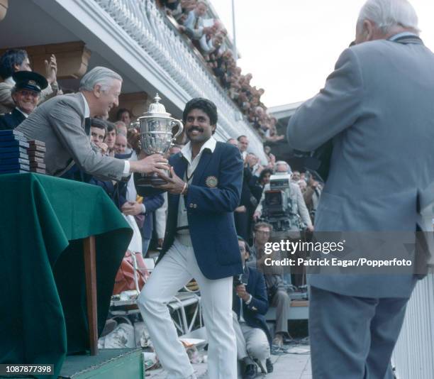 India's captain Kapil Dev is presented with the Prudential World Cup Trophy by Lord Carr of Hadley, chairman of Prudential Assurance, after India won...