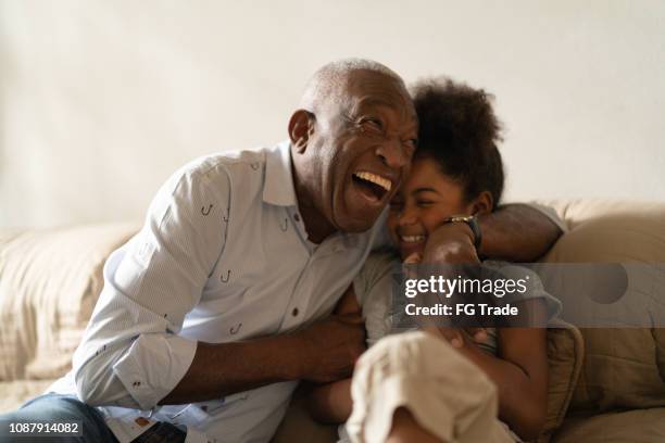 grandfather playing with her granddaughter at home - multi generation family photos imagens e fotografias de stock