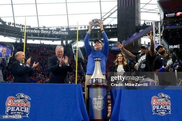 Head coach Dan Mullen of the Florida Gators hold the trophy after his teams win over the Michigan Wolverines during the Chick-fil-A Peach Bowl at...