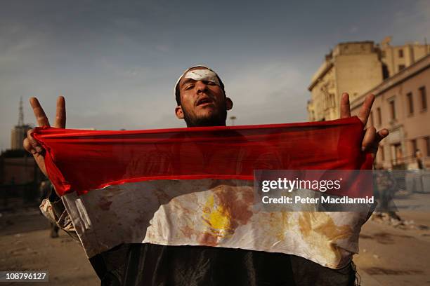 An anti-government protestor holds a blooded Egyptian flag in Tahrir Square on February 3, 2011 in Cairo, Egypt. The Army have positioned tanks...