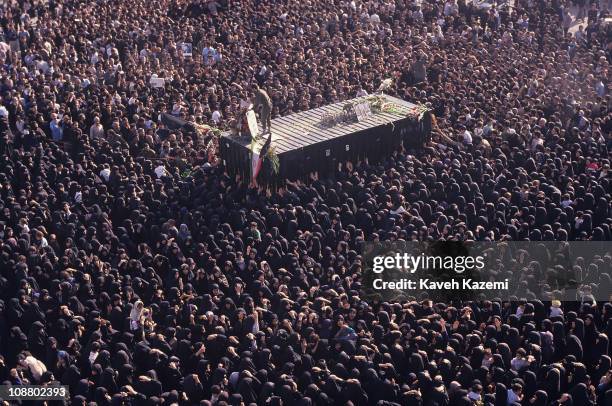 High-angle view of crowds of mourners as they surround the transport container used to move the body of Ayatollah Khomeini to a burial site, Tehran,...