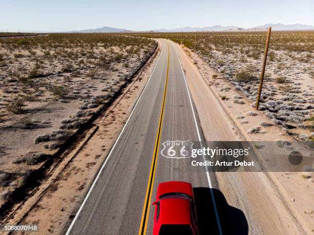 drone view of american car driving in a straight road at the california desert. - usa cars stock-fotos und bilder