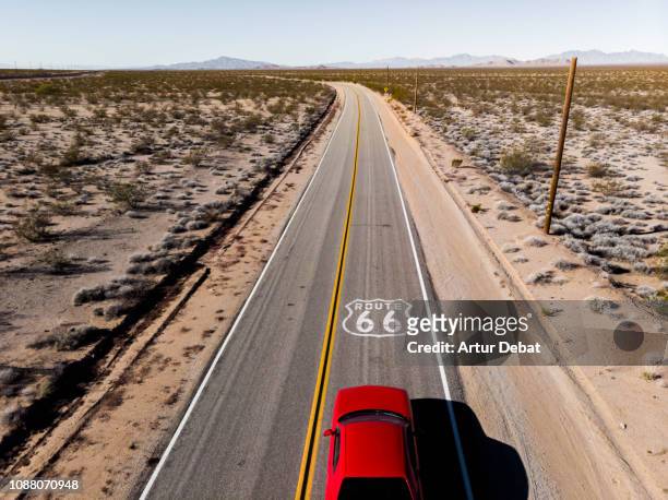 drone view of american car driving in a straight road at the california desert. - estados unidos del oeste fotografías e imágenes de stock