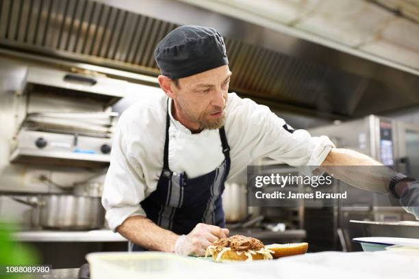 chef in kitchen near stove - chef hat stock pictures, royalty-free photos & images