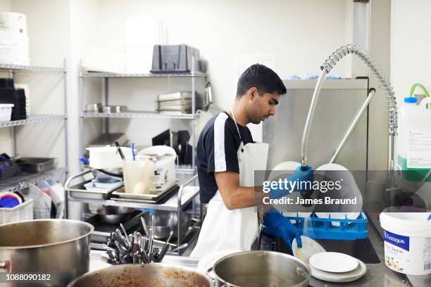 man washing dishes in commercial kitchen - faire la vaisselle photos et images de collection