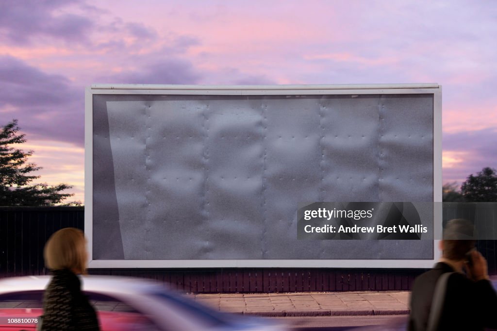 Blank billboard with passing pedestrians