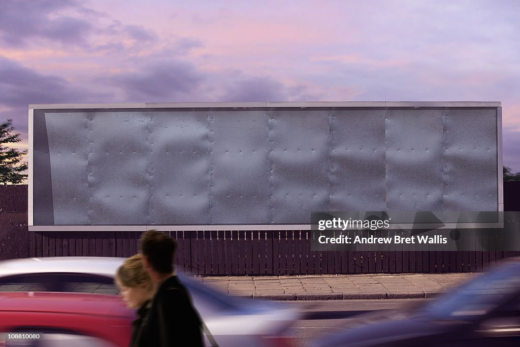 Blank billboard with passing pedestrians