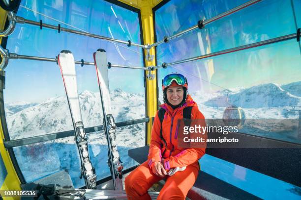 happy smiling skiing woman sitting in cable car - woman on ski lift stock pictures, royalty-free photos & images
