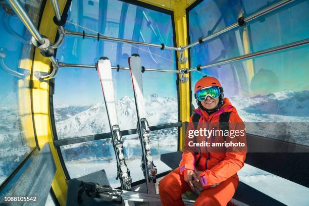 glimlachend skiën vrouw omhoog met de kabelbaan in winter bergen - cable car stockfoto's en -beelden