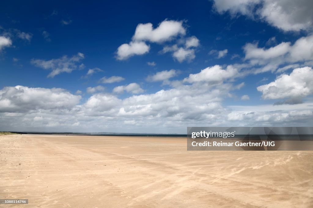 High wind on wide long St Andrews West Sands beach with blue sky and white clouds St Andrews Fife Scotland UK