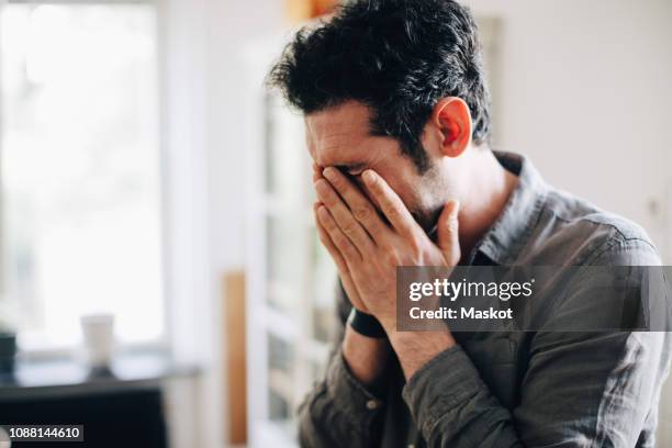 close-up of exhausted businessman covering mouth at home office - frustration man stock pictures, royalty-free photos & images