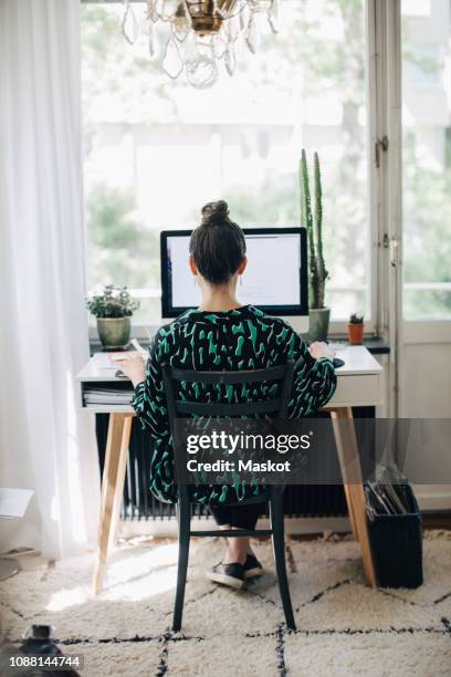 rear view of businesswoman using computer at desk in home office - home office stockfoto's en -beelden