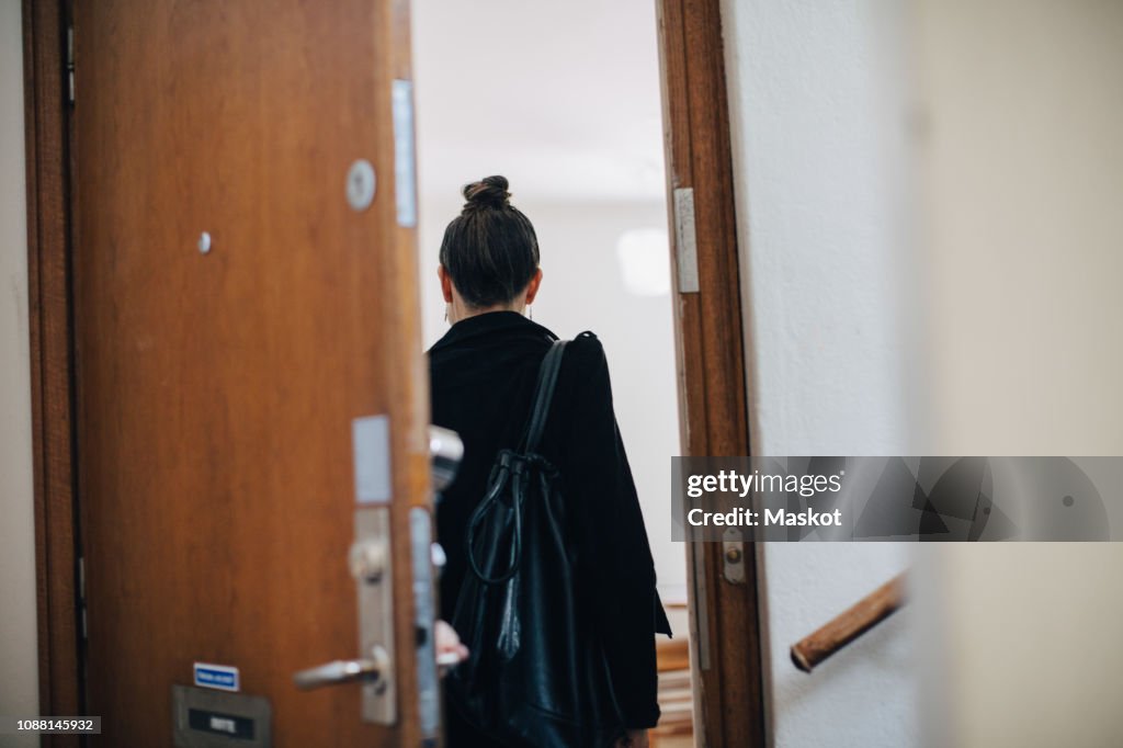 Rear view of businesswoman entering at coworker's apartment