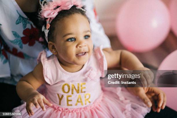 hermosa niña un año de edad, vestido de color rosa, celebrando su primer cumpleaños. - bebe 1 a 2 años fotografías e imágenes de stock
