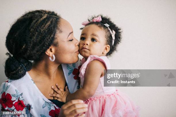 caring young mother and her one year old baby girl having fun together. - girl black dress stock pictures, royalty-free photos & images