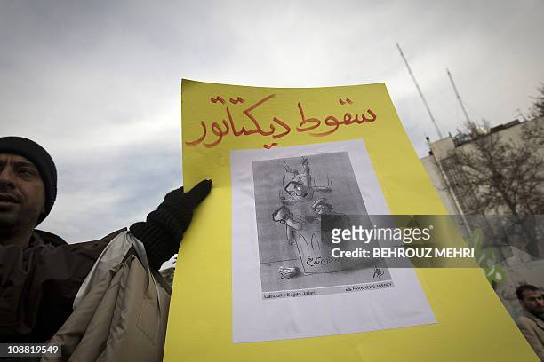 An Iranian man holds a cartoon depicting Egyptian President Hosni Mubarak joining Iran's late shah Mohammad Reza Pahlav and executed Iraqi dictator...
