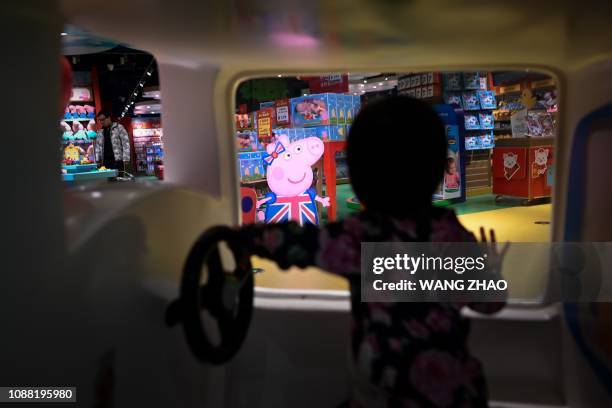 Girl looks at a billboard of Peppa Pig at a toy store in Beijing on January 25, 2019.