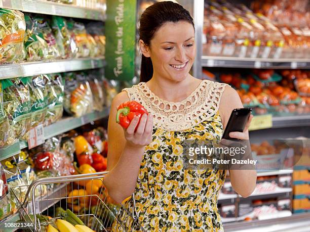woman checking shopping list on mobil phone - frugalidad fotografías e imágenes de stock