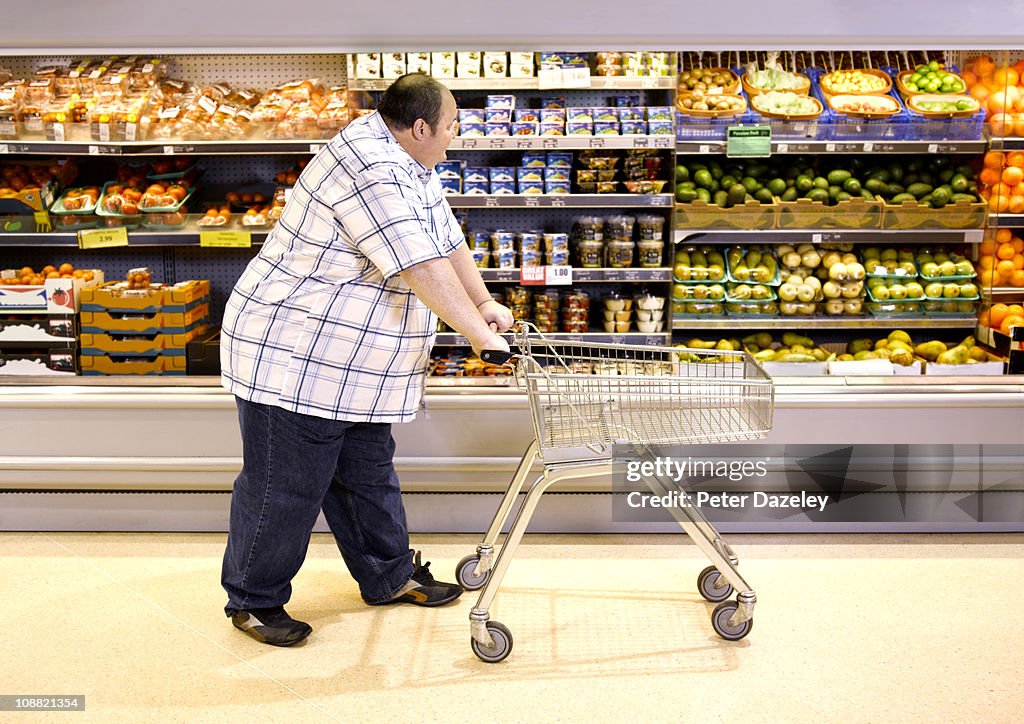 Overweight man passing by healthy food