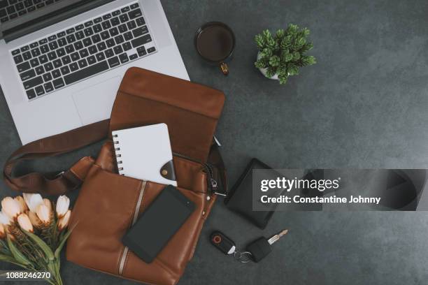 laptop, satchel leather bag, mobile phone and personal belongings on dark gray background - grey purse fotografías e imágenes de stock