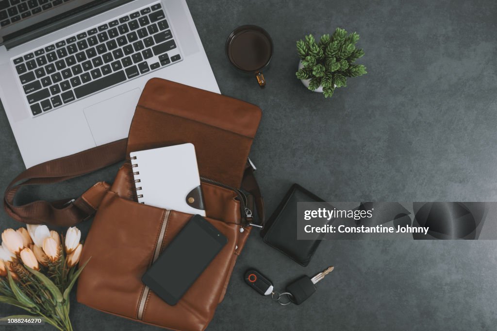 Laptop, Satchel Leather Bag, Mobile Phone and Personal Belongings on Dark Gray Background