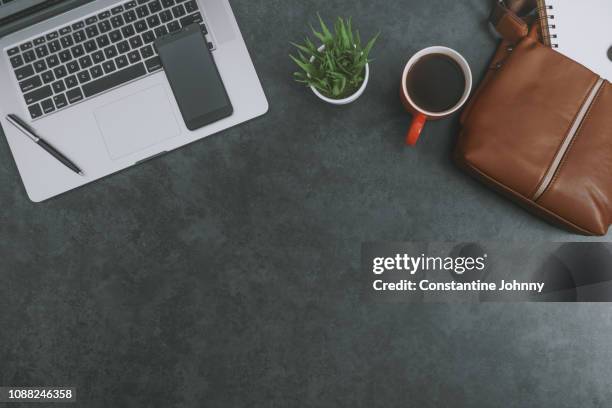 laptop, satchel leather bag, mobile phone and red coffee mug on dark gray background - grey purse fotografías e imágenes de stock