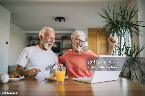 senior paar bieden op een online veiling - veiling stockfoto's en -beelden